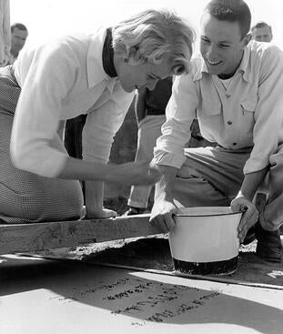 Student Lorraine Eyers (left) signs her name in cement.