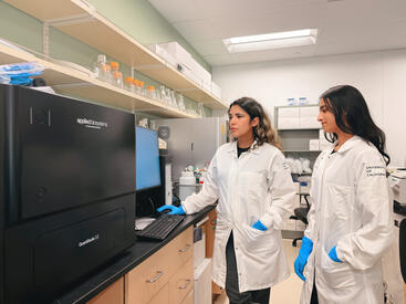 Sonali Chaturvedi with a trainee going over data on a digital PCR machine. 