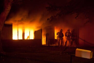 Firefighters battling fire consuming a home