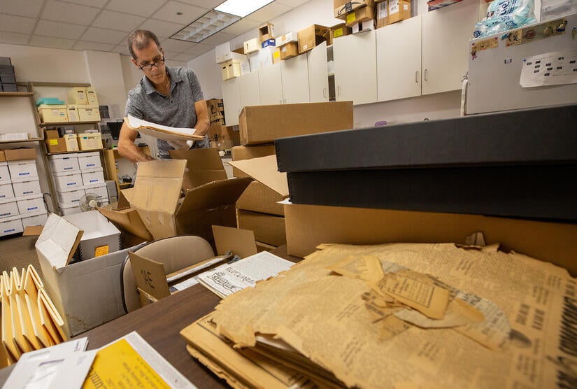 Brian Geiger, director of the Center for Bibliographical Studies and Research, goes through boxes of old newspapers in his office on Thursday, July 14, 2022, at UC Riverside. For the first time, 22 Southern California community newspapers will be archived, digitized, and available for the world. (UCR/Stan Lim)