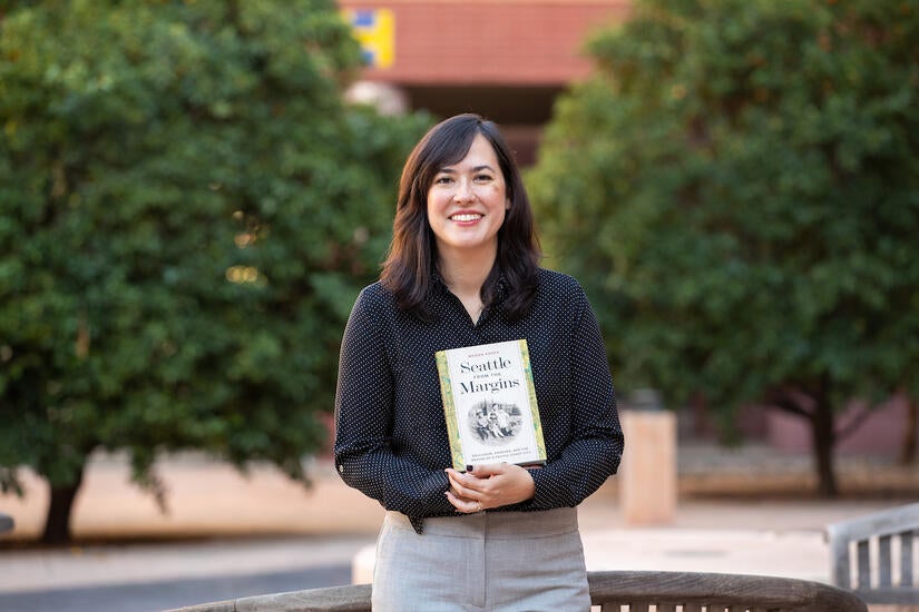 Megan Asaka, assistant professor of history, with her book, “Seattle from the Margins: Exclusion, Erasure, and the Making of a Pacific Coast City," on October 27, 2022, at UC Riverside.  (UCR/Stan Lim)
