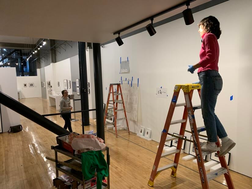 Grace Saunders (left) and Emily Gray work at the California Museum of Photography on March 7, 2023. They are setting up for the CMP's 50th anniversary exhibition. (UCR/Sandra Baltazar Martínez) 