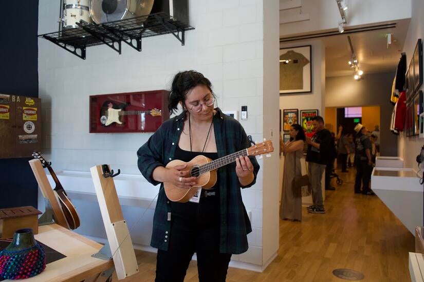A woman strums a ukulele on opening day of the exhibition.