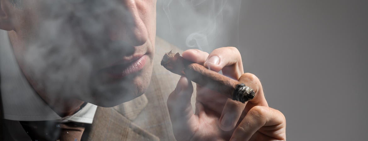 A well-dressed man smokes a cigar