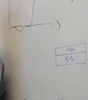 Researcher Jing Shi stands in front of white board