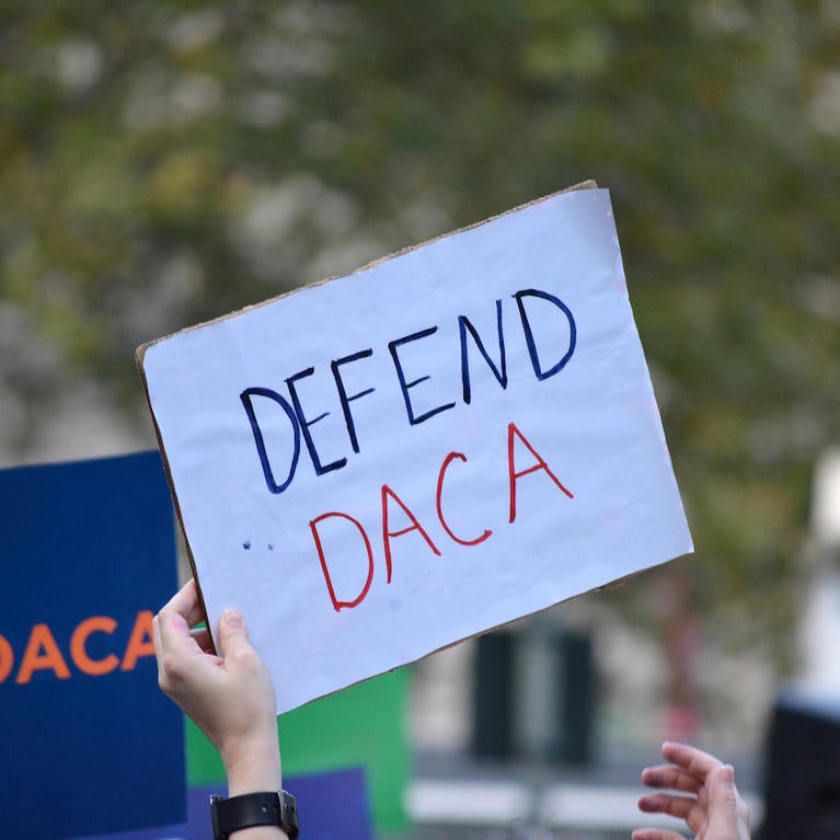 Supporters hold up a "defend DACA" poster at a rally 