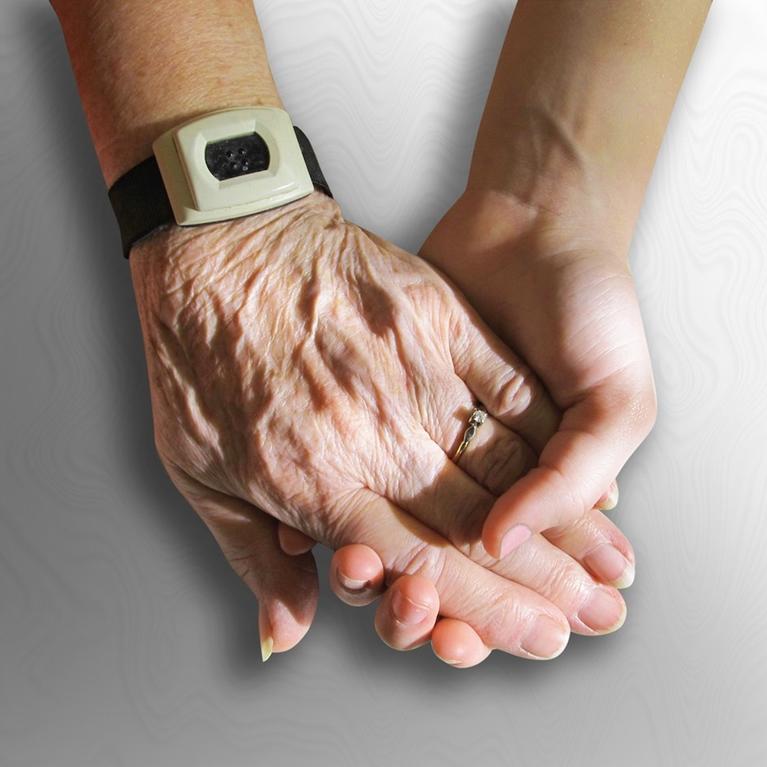 The hand of an old person holding the hand of a younger person