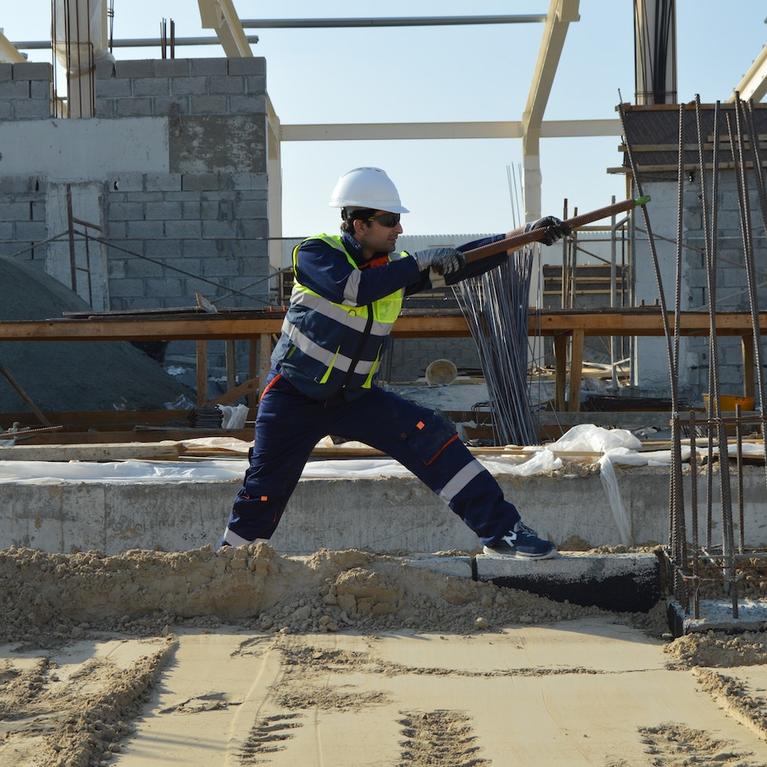 A construction worker bends rebar